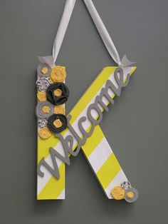 the letter k is made out of paper and decorated with buttons, ribbons, and flowers