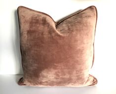 a brown velvet pillow sitting on top of a white table next to a wall mounted clock