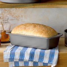 a loaf of bread sitting on top of a blue and white towel next to a pan