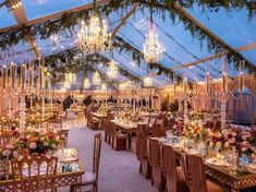 a large tent with tables and chairs set up for a formal dinner or function in the evening