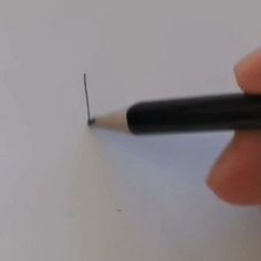 a person holding a pencil in their left hand and writing on the paper with a black marker