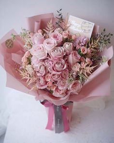 a bouquet of pink flowers is sitting on the table next to a card and envelope