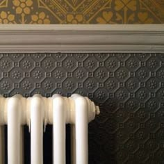 an old radiator is shown in front of a wall with ornate designs on it