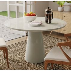 a white table with two chairs and a bowl of fruit on the dining room table