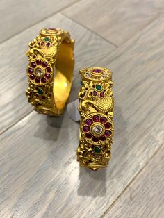 Temple bangle in matte gold and ruby stone. Detailing has the Rajasthani similarity. About an inch wide. Disclaimer: Price listed is for a single Kada. If you want to get them in a pair please select quantity 2. Festive Gold Bangle With Stone Setting, Festive Gold Bracelets With Stone Setting, Gold Bracelet With Stone Setting For Festivals, Gold Bracelets With Stone Setting For Festivals, Festive Gold Bangle With Peacock Design, Festive Gold Bracelets With Peacock Design, Gold Bangle Bracelet With Peacock Design, Gold Peacock Design Bangle Bracelet, Gold Bracelet With Stone Setting For Festive Occasion