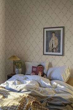 a bed with two pillows and a book on top of it next to a lamp