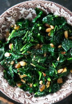 a bowl filled with greens and nuts on top of a table