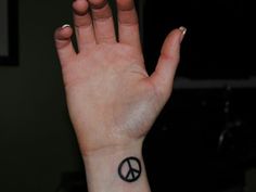 a hand with a peace sign tattoo on it's left wrist and the middle finger