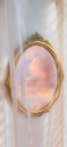 the sky is reflected in an ornate gold frame with white drapes hanging from it's sides