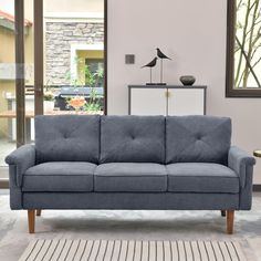 a blue couch sitting on top of a white rug in a living room next to a window