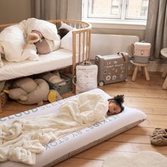 a small child laying on top of a mattress in a room with stuffed animals and toys