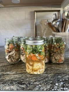 four mason jars filled with food sitting on top of a counter