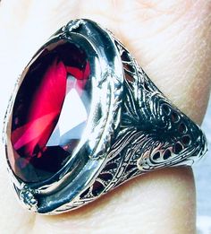 Simulated Red Ruby Ring GG Design#2 Custom Made Inspired by Victorian era designs, we have this lovely Antique filigree reproduction ring in sterling silver. There is 4 filigree flowers around the edge of the ring, notice the filigree which extends down the band. This well made setting is sterling silver and is marked 925. This is an eye popping, stunning, bezel set 16ct Simulated red ruby gemstone. This gorgeous gemstone is 17mm x 13mm in dimensions; just shy of 3/4th of an inch long by 1/2 inc Classic Red Ruby Ring, Oval Cabochon, Formal Oval Engraved Ring With Gemstone, Classic Red Ruby Ring With Oval Cabochon, Formal Oval Gemstone Engraved Ring, Oval Gemstone Engraved Ring For Formal Occasions, Collectible Fine Jewelry Ruby Ring With Polished Finish, Antique Red Signet Ring For Anniversary, Classic Ruby Ring With Polished Finish For Collectors, Heirloom Red Signet Ring With Polished Finish