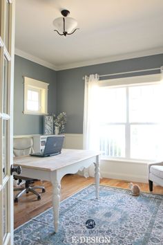 a laptop computer sitting on top of a white desk in front of a large window