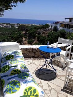 an outdoor patio with table and chairs overlooking the ocean