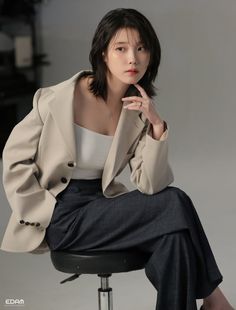 a woman sitting on top of a chair wearing a white shirt and blazer jacket