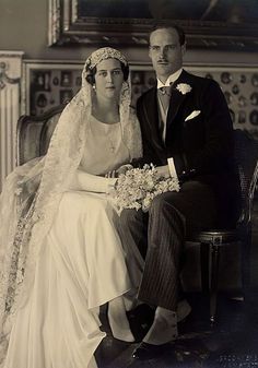 an old black and white photo of a man and woman in wedding attire sitting on a chair