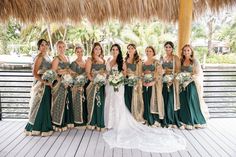 a group of women standing next to each other in front of a tiki hut