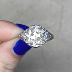 a woman's hand holding an old - fashioned diamond ring with blue nails on it