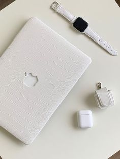 an apple laptop computer sitting on top of a table next to two other electronic devices