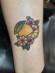 a tattoo on the leg of a woman with fruit and flowers around her ankles,