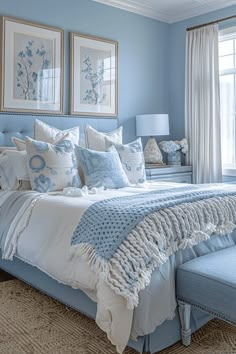 a bedroom with blue walls and white bedding in the center, along with two framed pictures on the wall