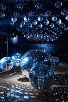 several shiny balls are suspended from the ceiling in an empty room with lights shining down on them