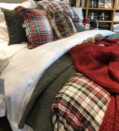 a bed covered in blankets and pillows next to a book shelf