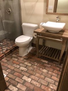 a white toilet sitting next to a sink in a bathroom under a mirror and shower