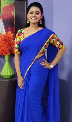 a woman in a blue sari posing for the camera with her hands on her hips