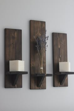 three wooden wall shelves with candles and flowers on them, one is made out of wood