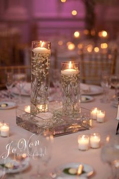 two clear vases filled with flowers on top of a table covered in plates and silverware