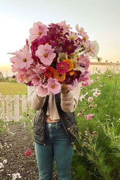 a woman holding up a bunch of flowers