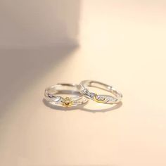 two gold and silver rings sitting on top of a white table next to each other