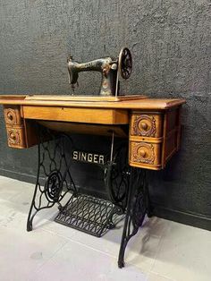 an old sewing machine sitting on top of a wooden table next to a gray wall