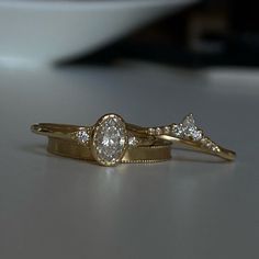 two gold wedding rings with diamonds on them sitting on a countertop in front of a white plate