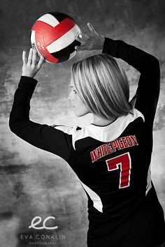 a woman holding a volleyball ball in her right hand while wearing a black and white uniform