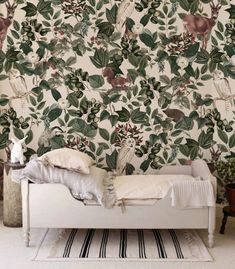 a white bed sitting next to a wall covered in green leaves and animals on it