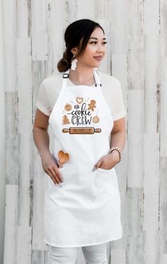 a woman is wearing an apron and has her hands on her hips while standing in front of a wooden wall