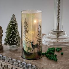 a glass candle holder sitting on top of a wooden table next to green candies