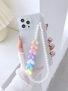 a woman is holding up her phone case with colorful beads and pearls on the back