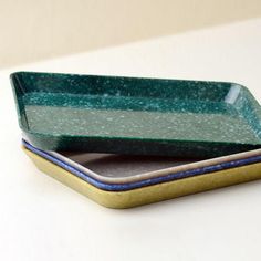 a green and blue dish sitting on top of a white table