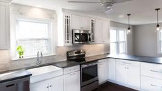 an empty kitchen with white cabinets and black counter tops is seen in this image from the front view