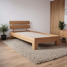 a wooden bed frame sitting on top of a carpeted floor next to a potted plant