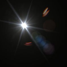 the sun shines brightly in the dark sky with lens flares on its side