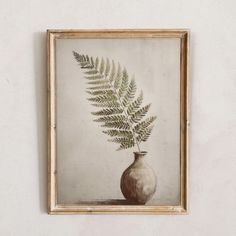 a painting of a fern in a vase on a wall above a framed photo frame