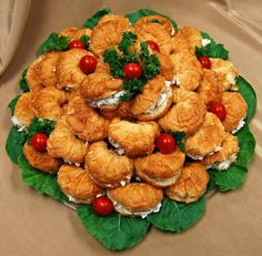 a platter filled with croissants and tomatoes on top of green leaves