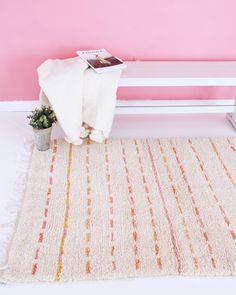 a white bench sitting next to a pink wall with a potted plant on it