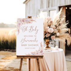 a welcome sign sitting on top of a wooden easel next to a white table