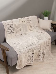 a white crocheted blanket sitting on top of a couch next to a wooden chair